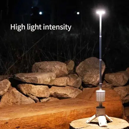 Outdoor light fixture illuminating a stone wall and wooden bench at night.
